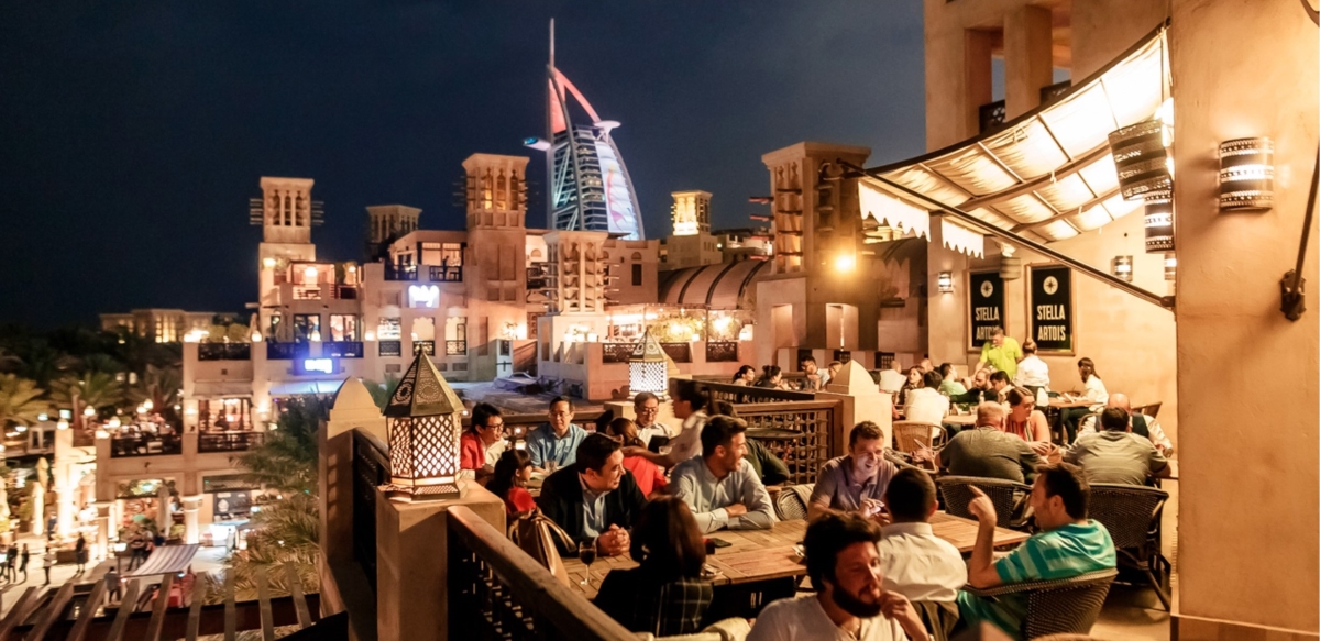 Outdoor seating with guests dining at Belgium Beer Cafe in the evening with the iconic Burj Al Arab in the background